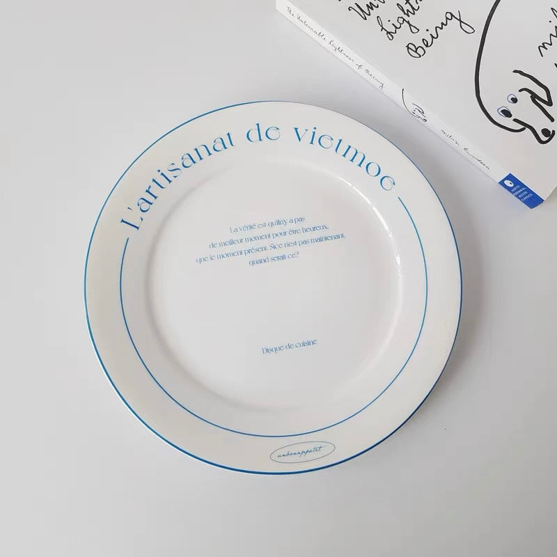 Double handle white pottery bowl with blue printed French lettering and compact rounded bowl shape