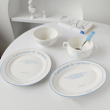 French bistro tableware including white plates bowls and handled dishes with fine blue printed typography