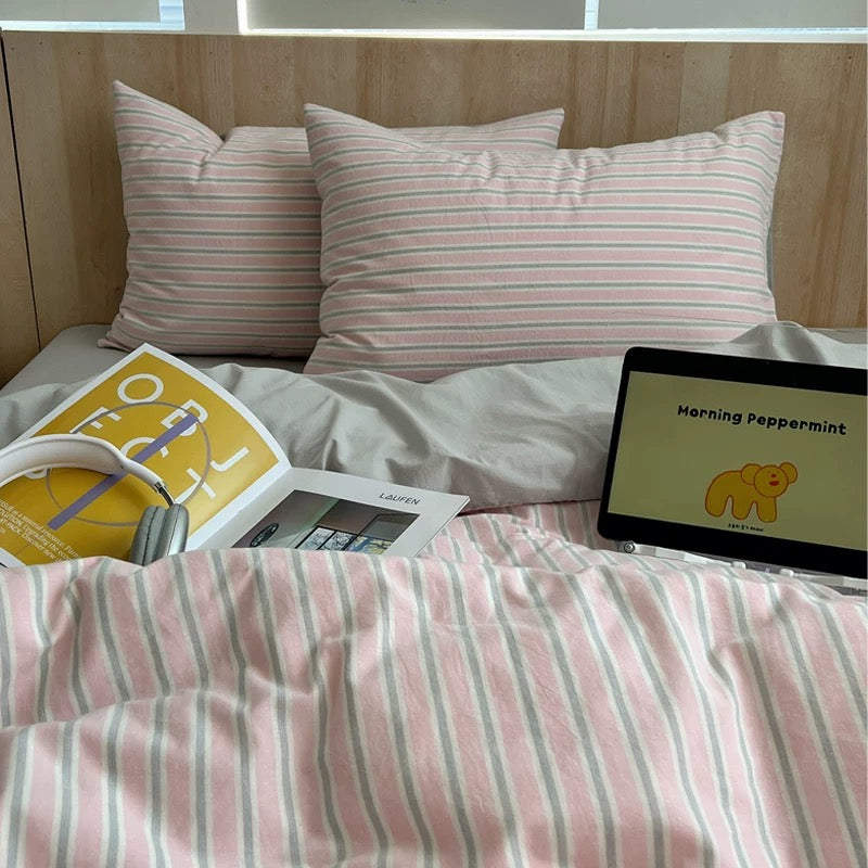 Bed with pink and white striped bedding, a book, and a tablet displaying 'Morning Peppermint'.