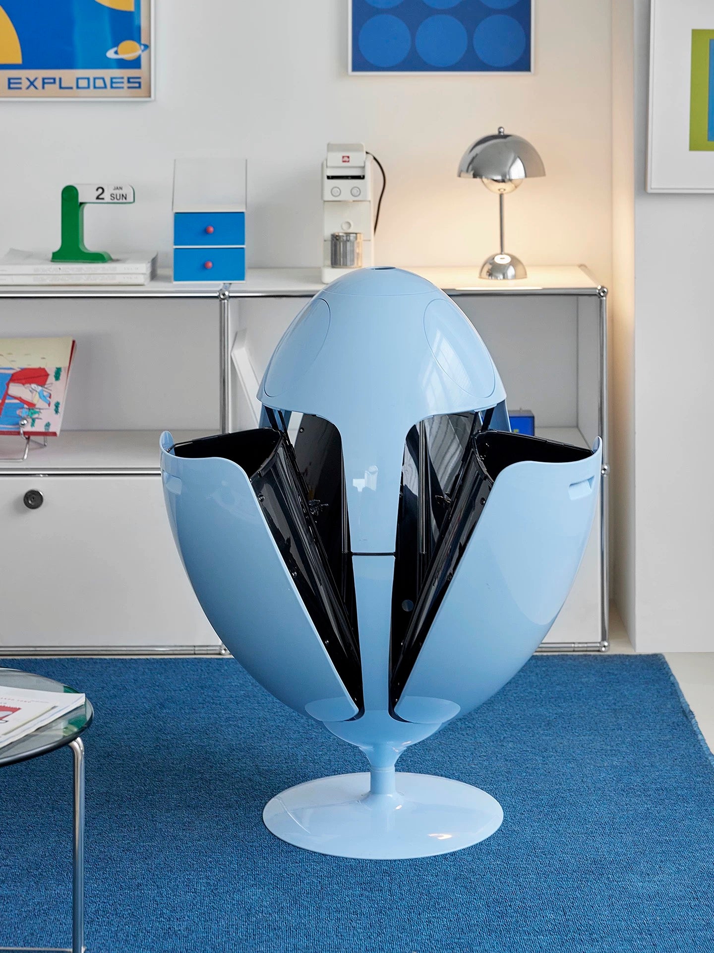 Modern blue egg-shaped chair in a room with a desk and decor.