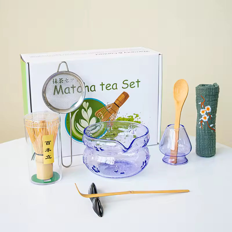 Matcha tea set with various tools and a branded box on a white surface.