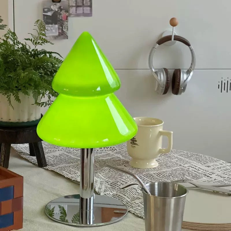 Green tree-shaped stool in a room with a cup and spoon on a table.