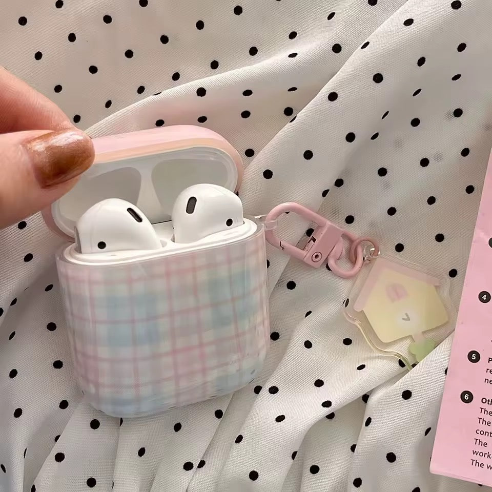 Pink plaid AirPod case with white AirPods on a polka dot fabric background