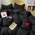 4-piece cotton bedding set featuring black duvet, sheet, and heart pillows