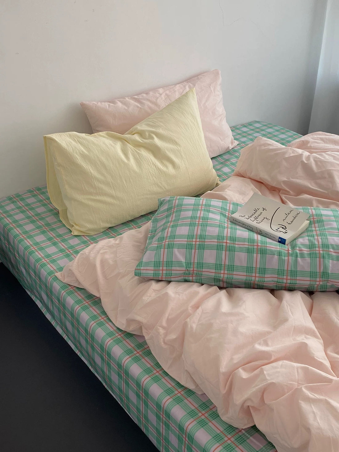 Bed with pink and green checkered bedding and pillows.