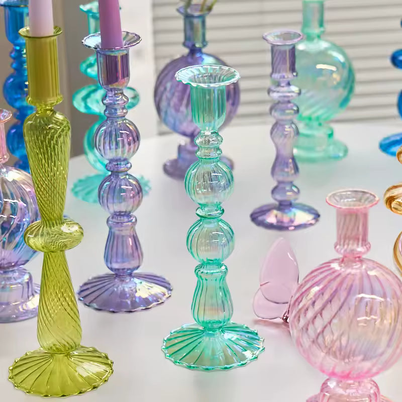 Colorful glass candlesticks and vases on a white surface