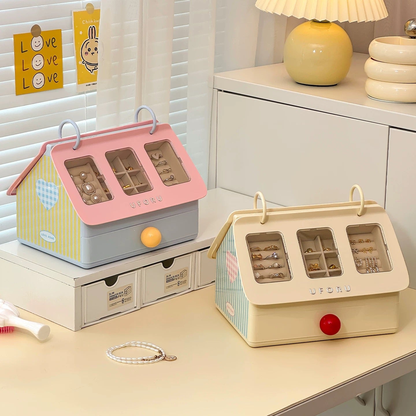 Two small jewelry boxes on a desk with a lamp in the background