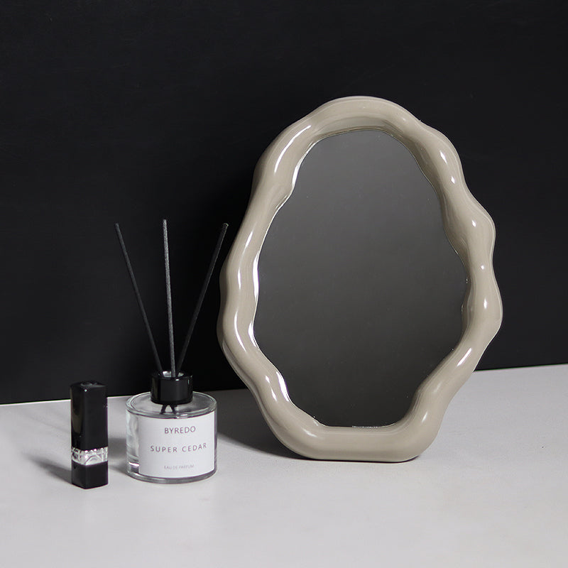 Decorative mirror with a black background and Byredo perfume bottle on a white surface