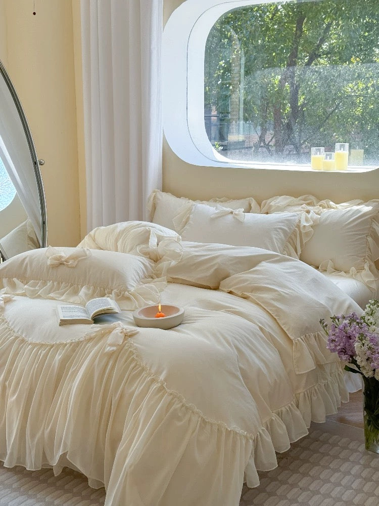 Neatly made bed with white bedding in a room with a window and curtains.