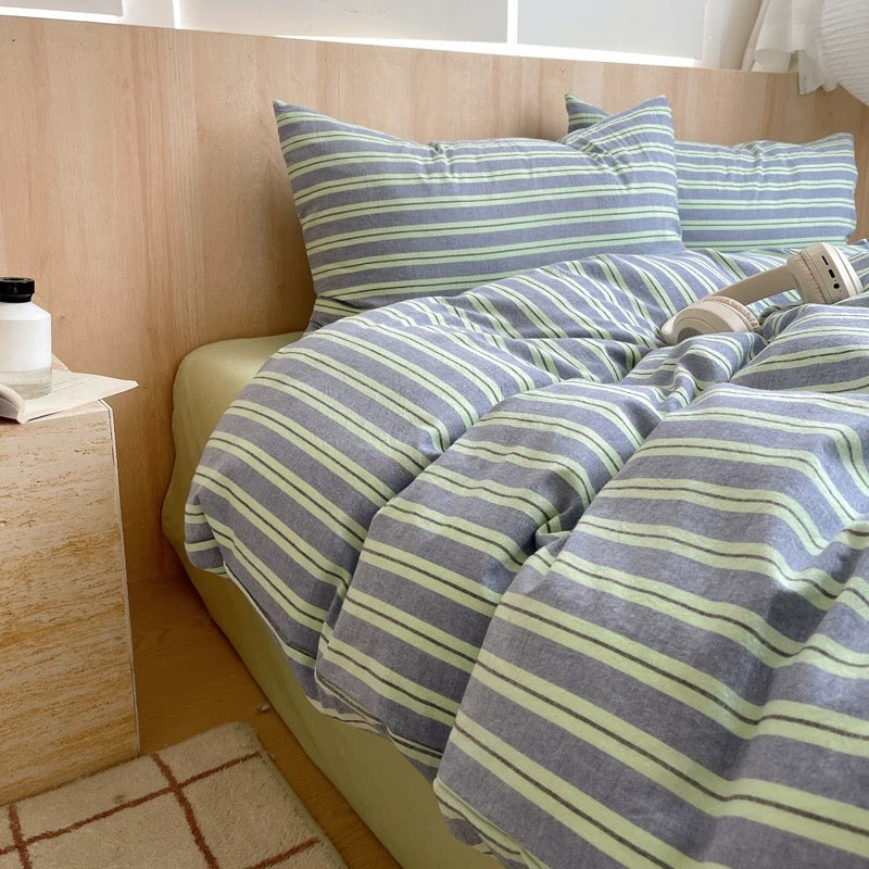 Striped bedding on a bed with a wooden headboard and nightstand.
