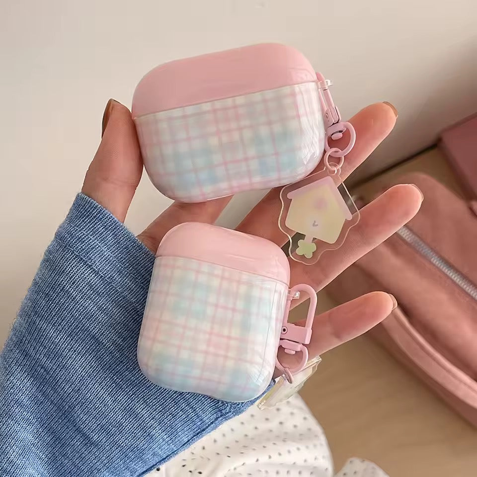 Pink and white checkered air pod cases held by a hand with a blue sleeve.