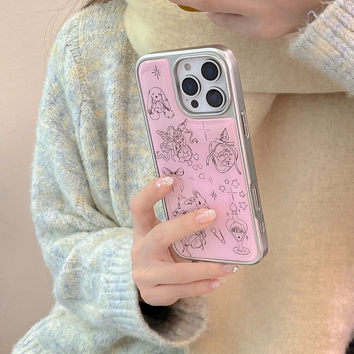 Person holding a phone with a pink case featuring cute illustrations.