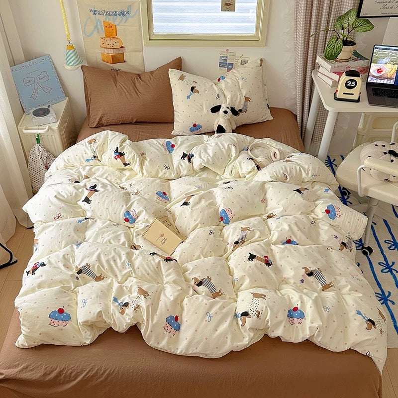 White quilt with cartoon designs on a bed in a room with a desk and window.