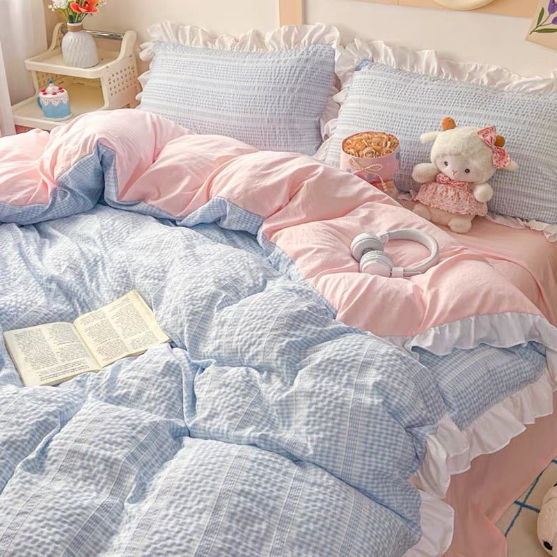 Bedroom with pink and blue bedding, pillows, and stuffed toys.