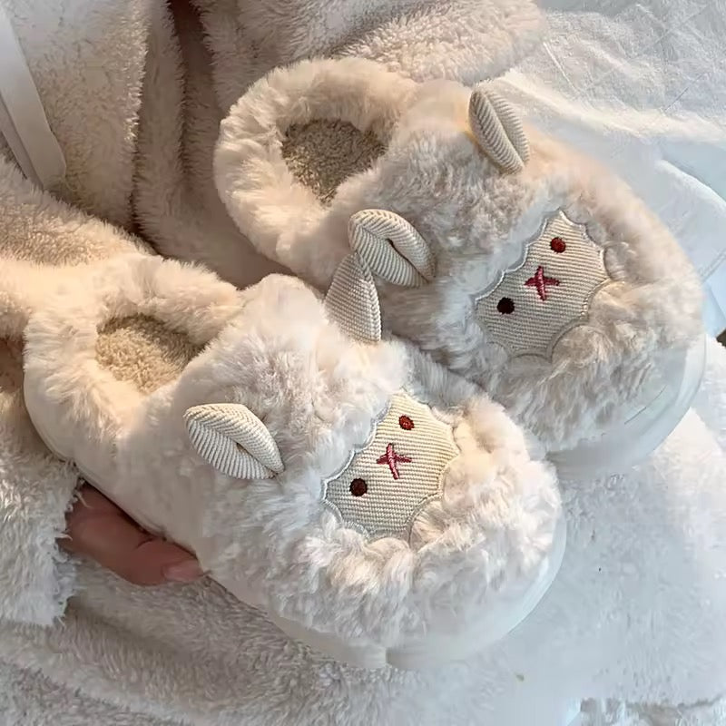 Pair of fluffy white slippers with bunny ears held against a soft fabric background