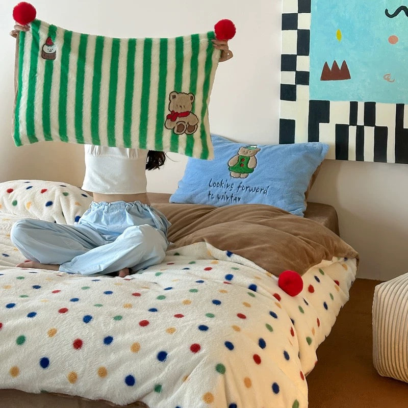 Children's bedroom with polka dot bedding, teddy bear, and colorful wall art.