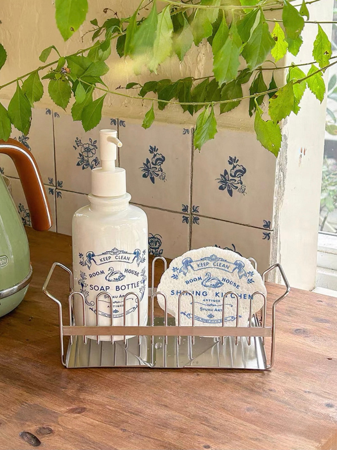 Kitchen soap dispenser stands inside a stainless steel rack beside a matching blue and white dish sponge.