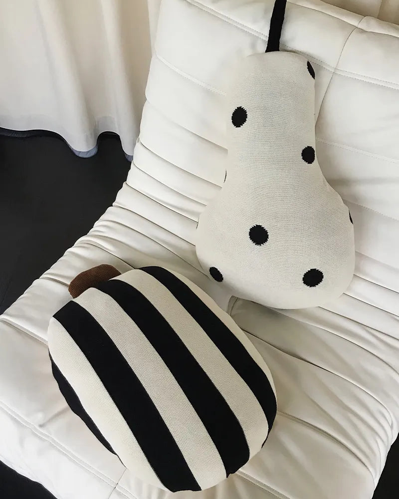 Two decorative pillows, one with black and white stripes and the other with black polka dots, on a white cushion.