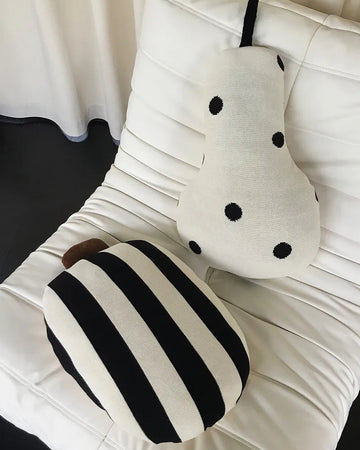Two decorative pillows, one with black and white stripes and the other with black polka dots, on a white cushion.