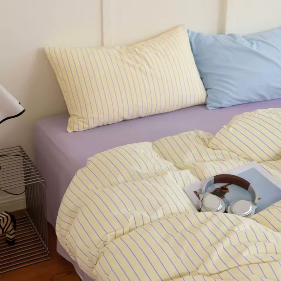 Bed with yellow striped bedding and pillows in a bedroom setting