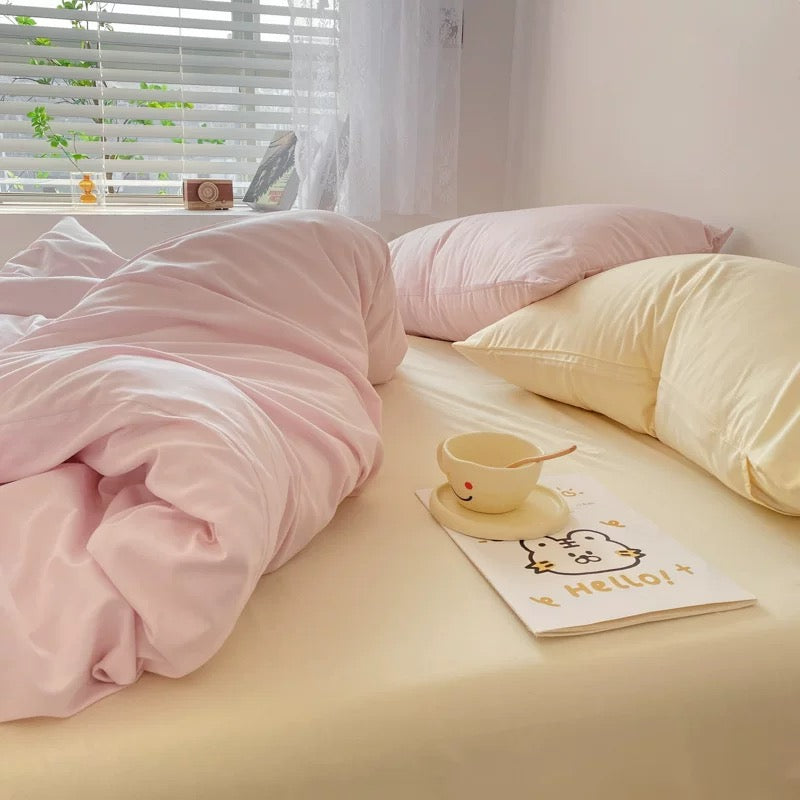 Pastel pink and cream bedding set with soft duvet cover and pillowcases styled in a cozy bedroom.