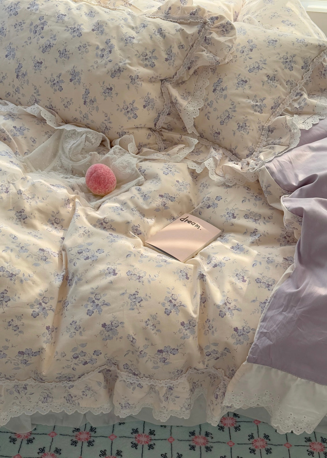 Floral-patterned bedspread with a pink plush toy and a book on a bed.