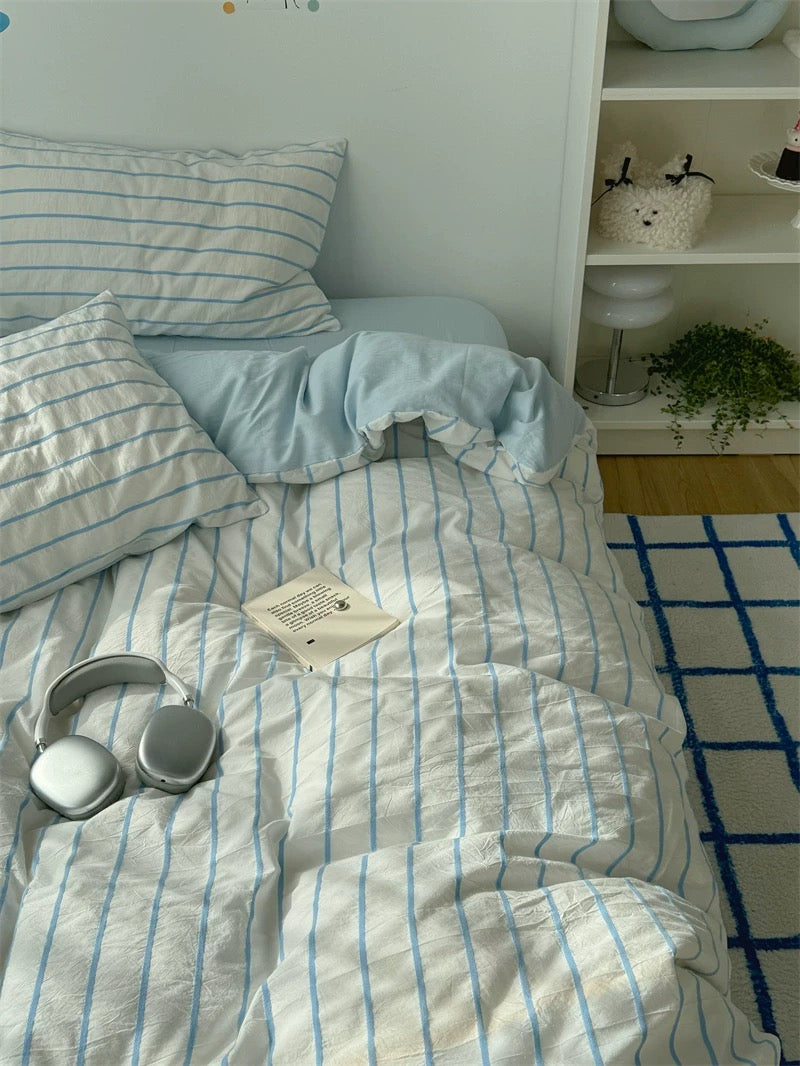 Bed with striped bedding in a room with shelves and decor