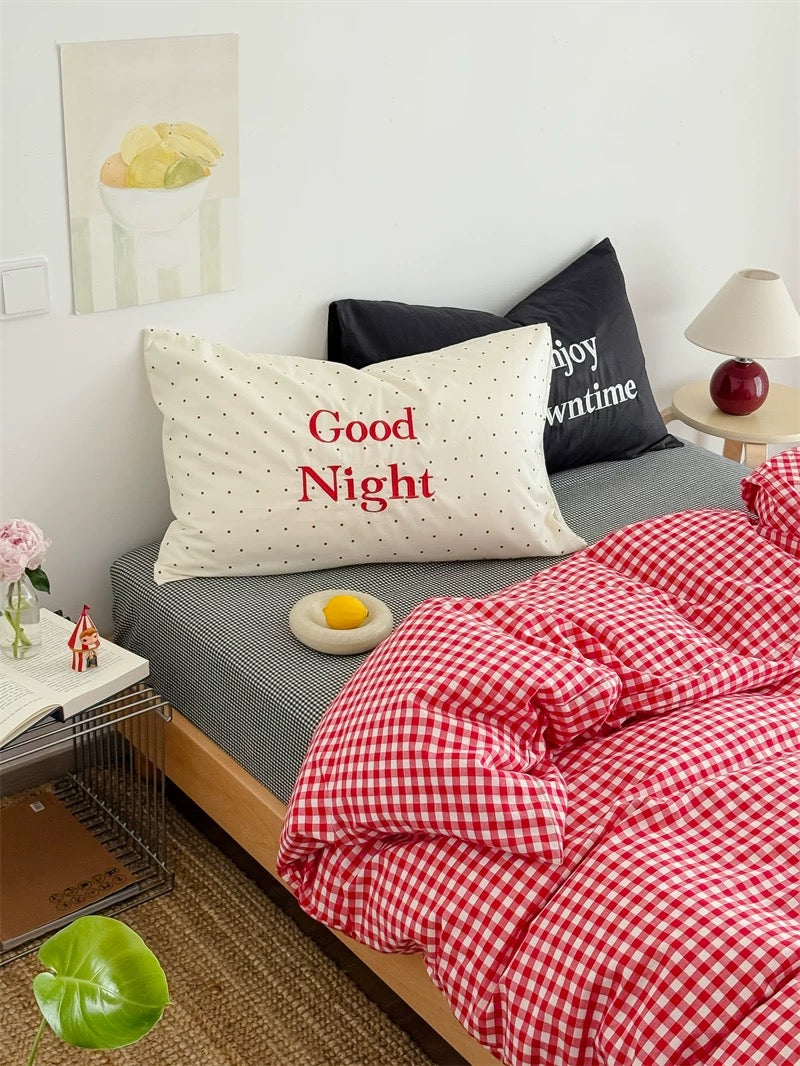 Bedroom with a bed featuring a 'Good Night' pillow and red checkered duvet.