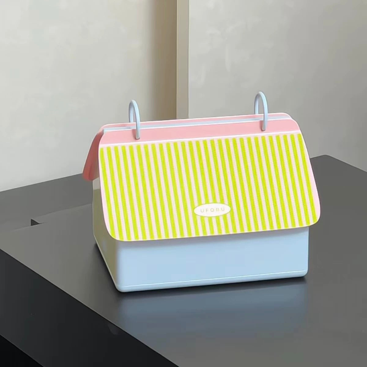 Yellow striped bag with pink top on a gray surface