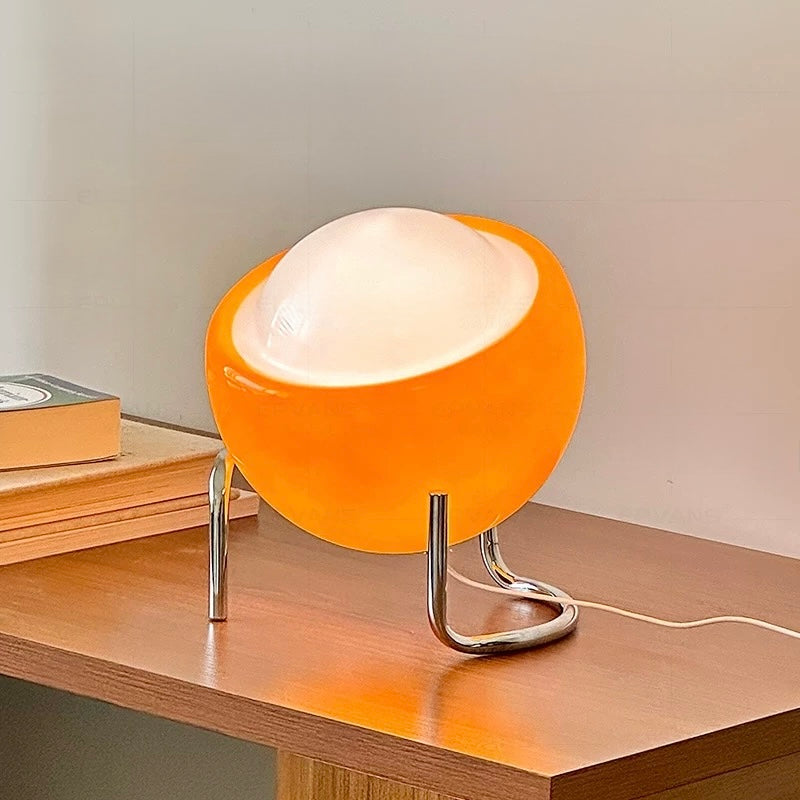 Orange table lamp with a white shade on a wooden surface.