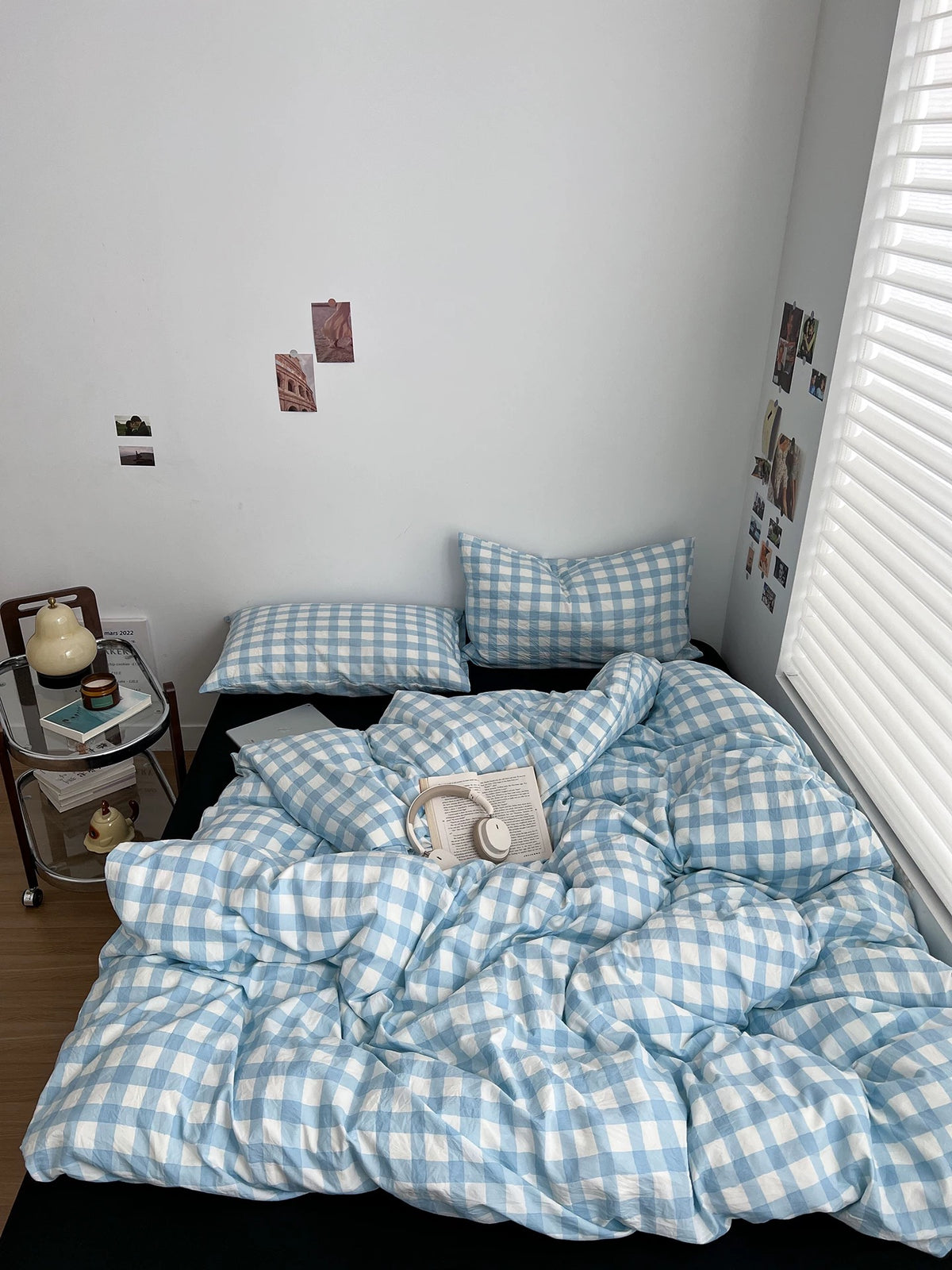 Light blue gingham bedding for a dorm-style bedroom with black pillows and wall decor