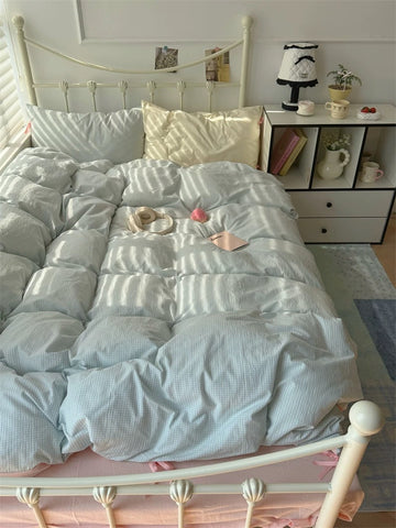 Bed with light blue comforter and decorative items in a bedroom setting.