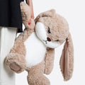 The plush toy seated on a bed, demonstrating its size and suitability for decor.