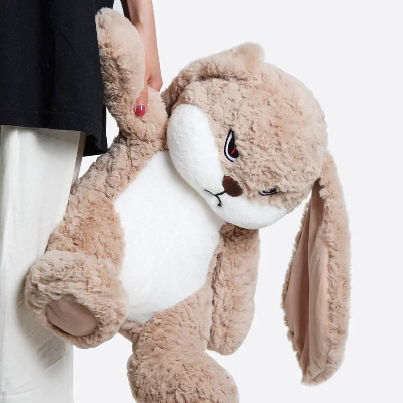 The plush toy seated on a bed, demonstrating its size and suitability for decor.