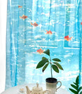 Decorative curtain with fish and underwater scene, placed on a table with a plant and teapot.
