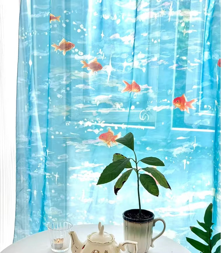 Decorative curtain with fish and underwater scene, placed on a table with a plant and teapot.