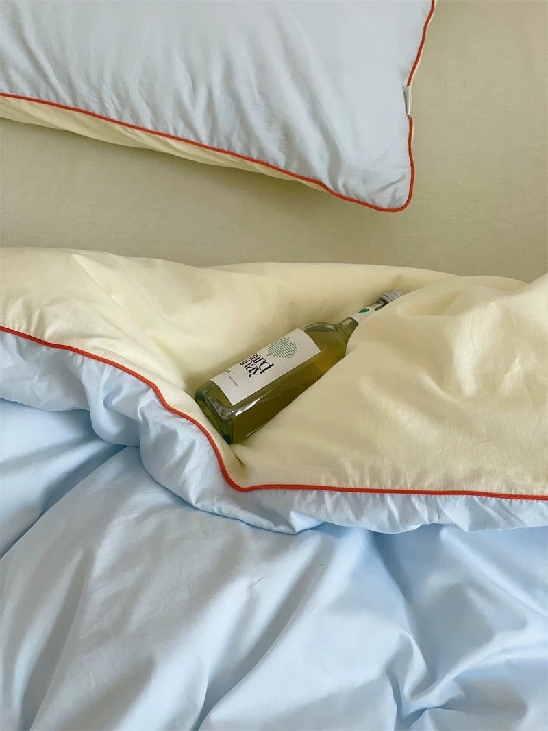 Green bottle of olive oil on a white pillow with red trim.
