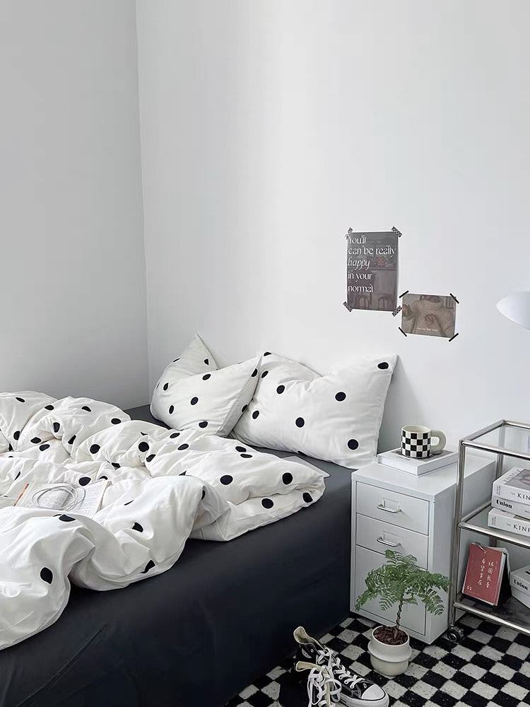 Bedroom with polka dot bedding and a nightstand.