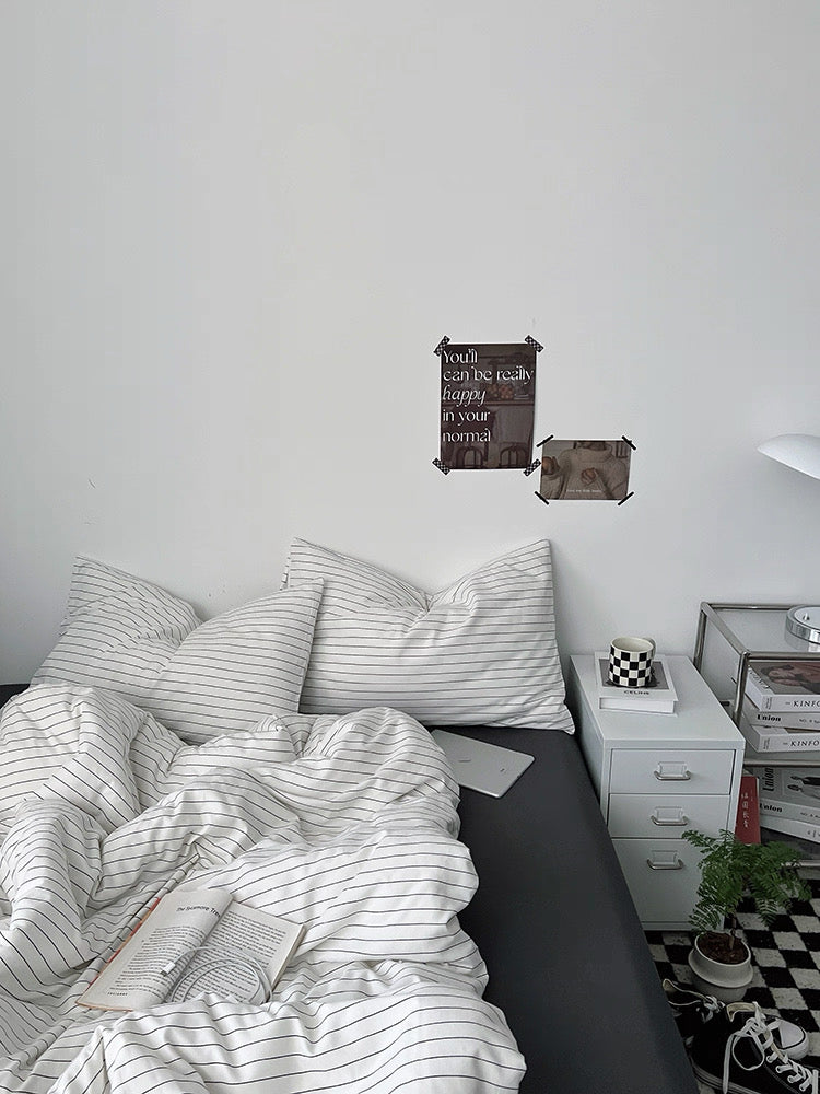 Bedroom with striped bedding and nightstands, featuring a motivational poster on the wall.