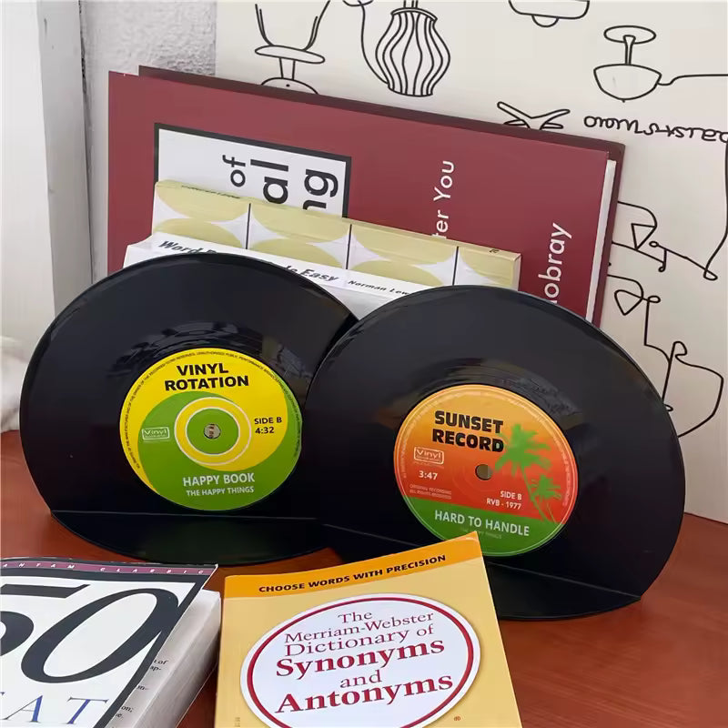 Two vinyl records with colorful labels on a surface with books and a dictionary.