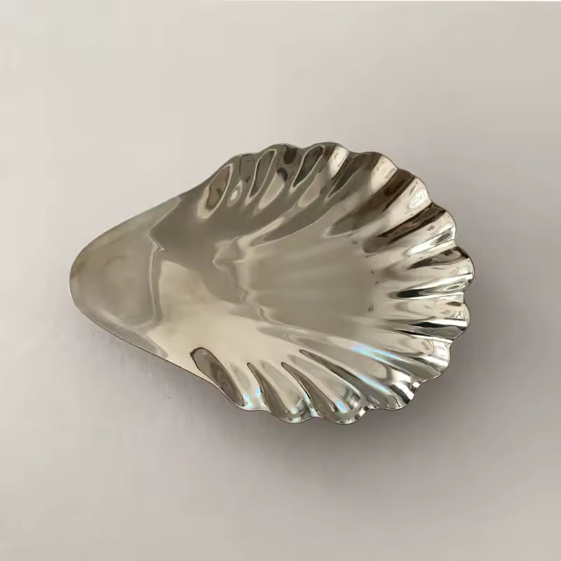 Silver shell-shaped object on a light gray background