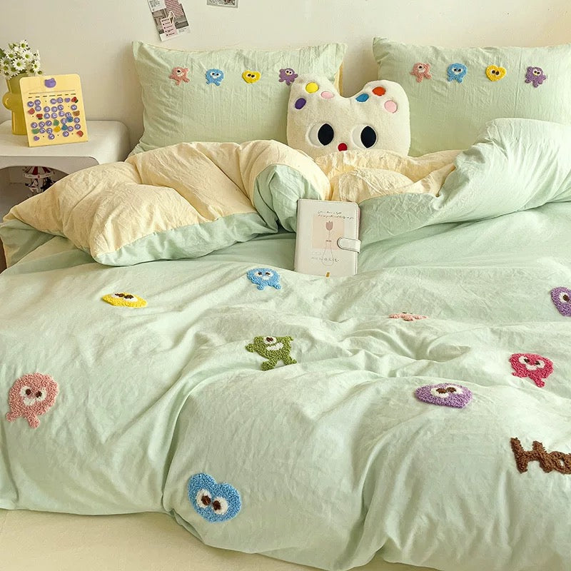 Mint green duvet and pillowcases with colorful cartoon embroidery and pale yellow bedding accents.