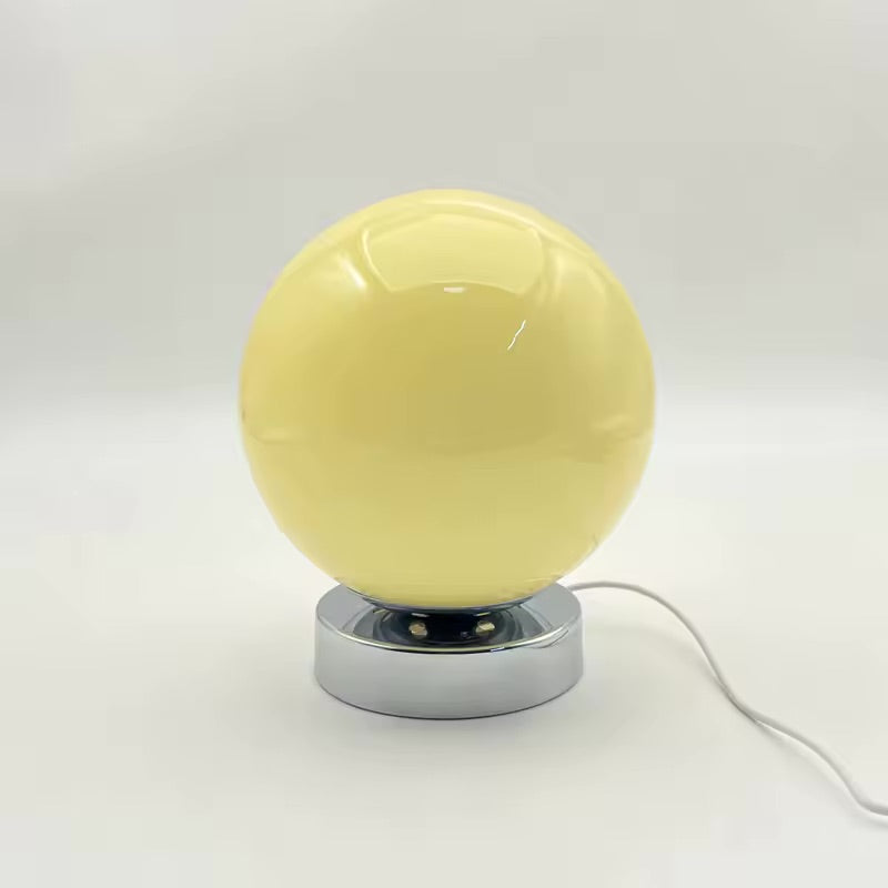 Yellow spherical lamp with a chrome base on a white background