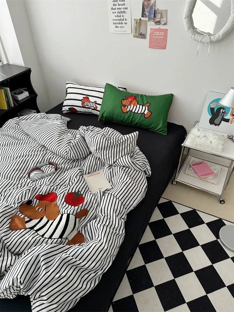 Bed with striped bedding featuring cartoon characters, black and white checkered floor, and a small table with items.
