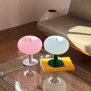 Two small round stools with colorful tops on a glass table.