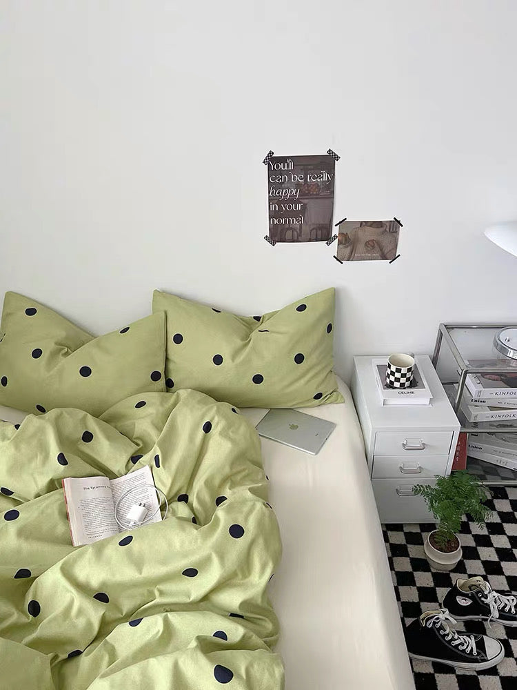 Bedroom with green polka dot bedding and a white nightstand.