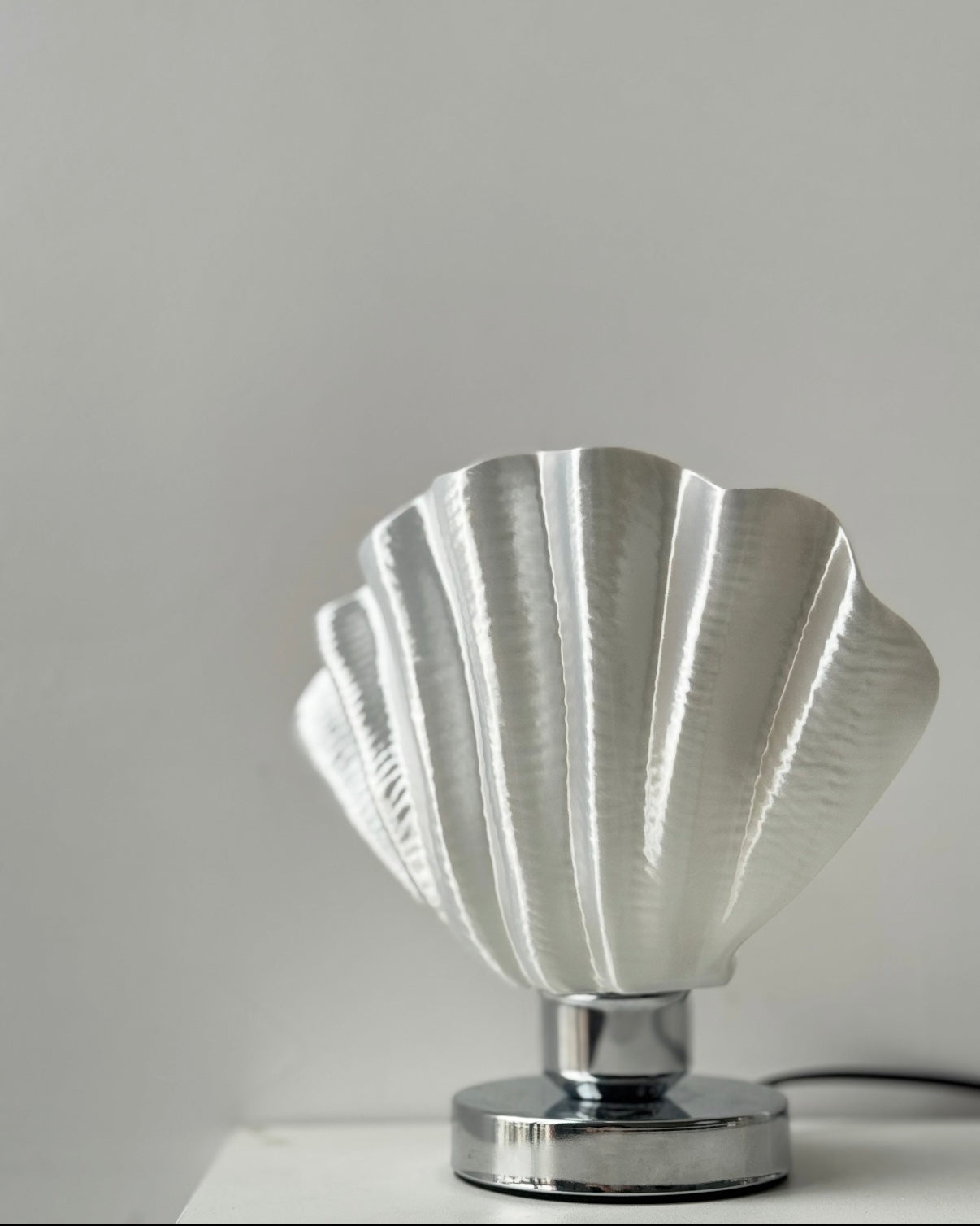 White scallop lamp with sculptural relief shade displayed on modern bedroom nightstand