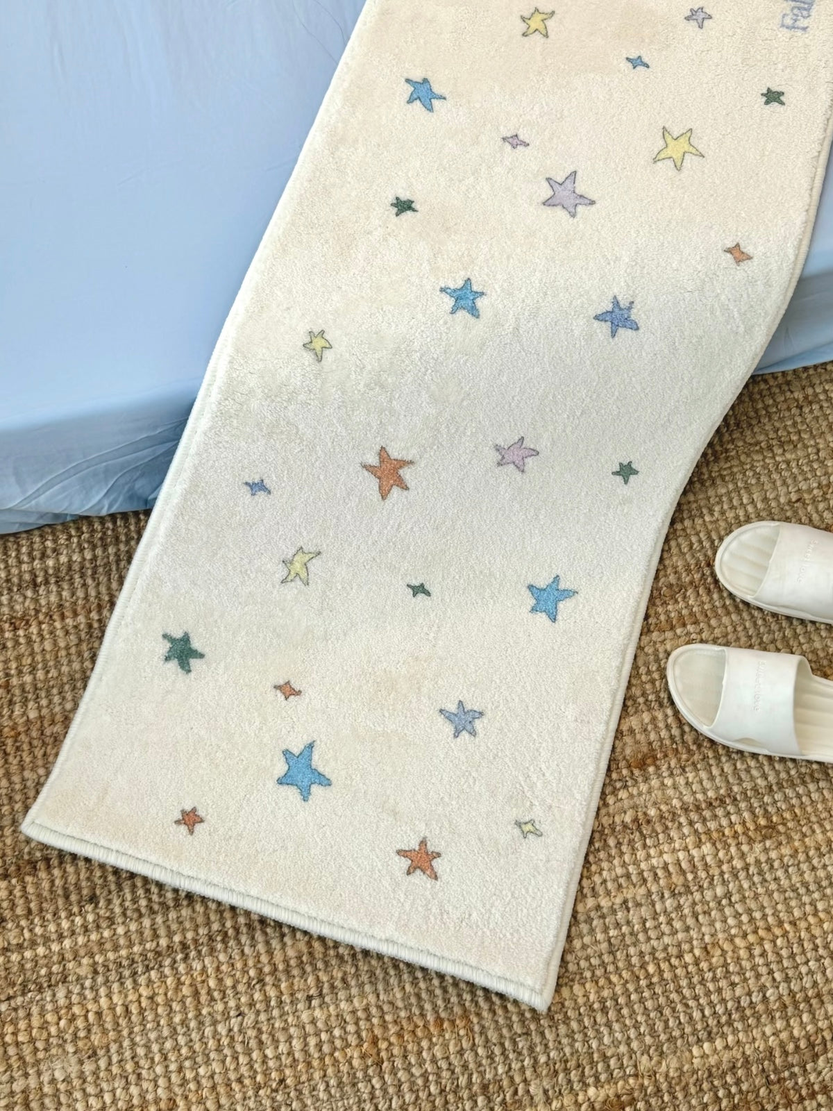 A multicolor star rug curves upward along its length, showing the star pattern beside white slippers.