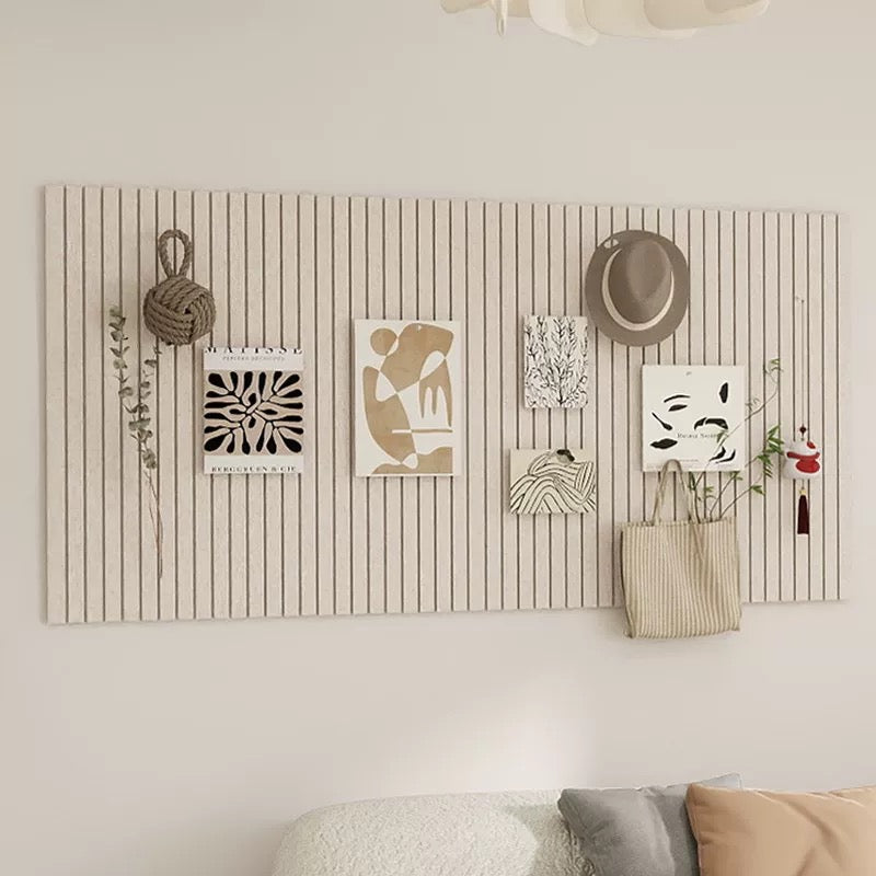 Wall-mounted board with decorative items including a hat, plants, and bags against a neutral wall.