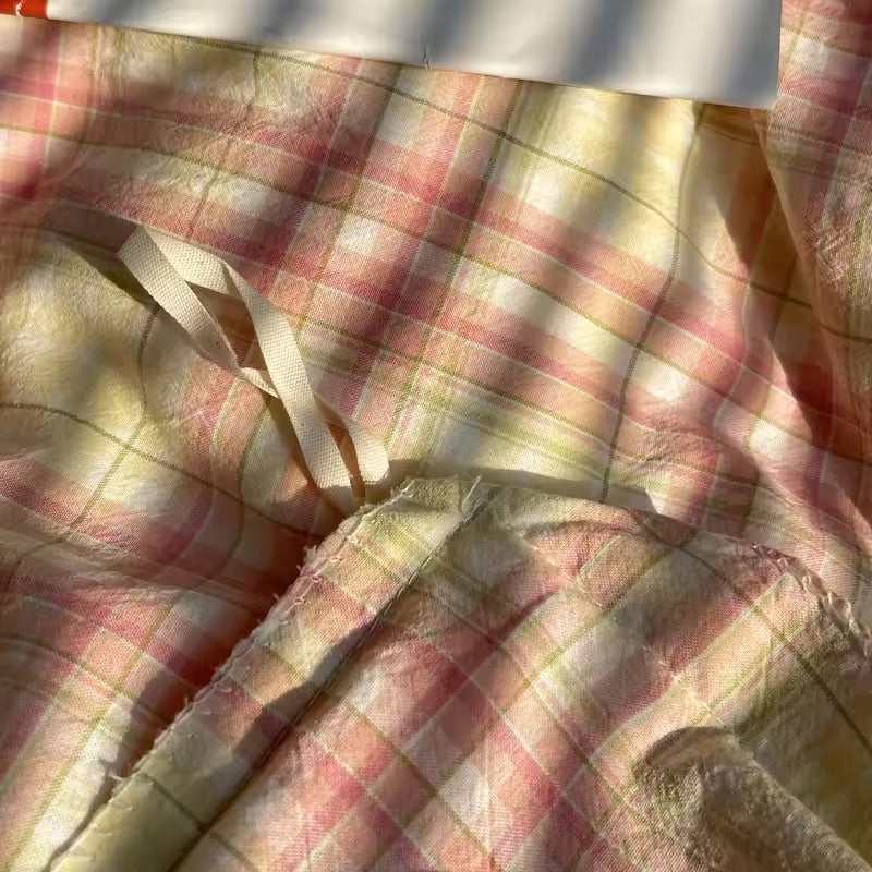 Plaid fabric with a visible seam and thread, showing signs of wear.